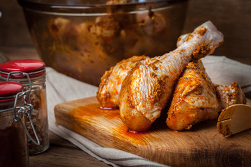 Marinated chicken drumsticks on a wooden chopping board.