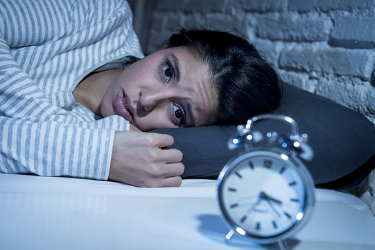 hispanic woman at home bedroom lying in bed late at night trying to sleep suffering insomnia