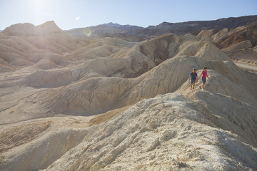 A man and woman hiking on the hilly, moon-like landscape of Death Valley.  California.