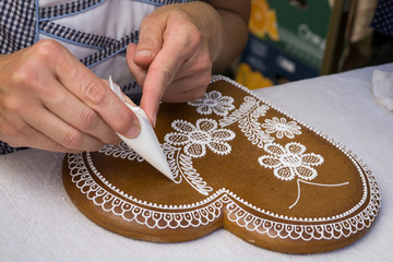 Zilina, Slovakia - September 25, 2016. Woman decorating a heart shaped honey cake process on table during National markets of home-made goods and arts. 