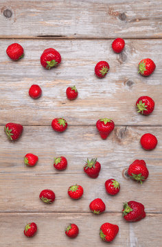 Fresh strawberries  scattered on a wooden surface