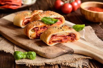 Traditional Italian Stromboli stuffed with cheese, salami, green onion and tomato sauce