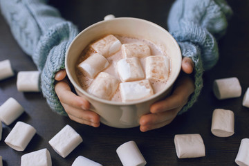 girl holding in hands a big Cup of coffee with marshmallows
