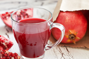 Glass of pomegranate juice with fresh fruits on white rustic wooden table