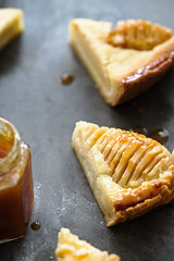Cut of pear almond cream tart with apricot glaze. Dark grey background