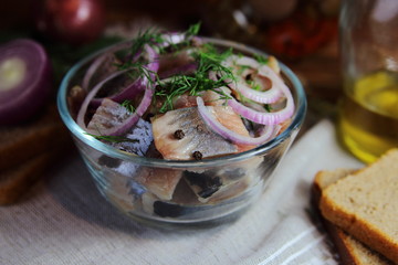 сельдь с луком и укропом в стеклянной тарелке