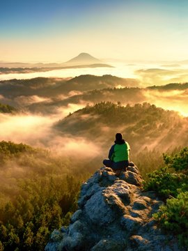 Man tourist sit on exposed rock. View point with heather and branches