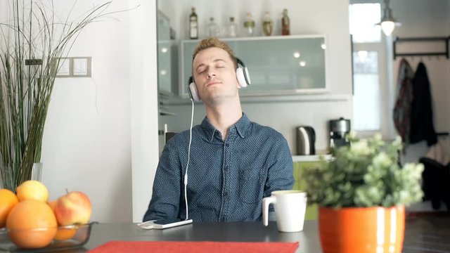Red haired man listening music and smiling to the camera
