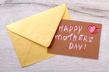 Mother`s day card and envelope. Envelope on wooden backdrop. Remember to send greeting. Congratulation letter for mom.