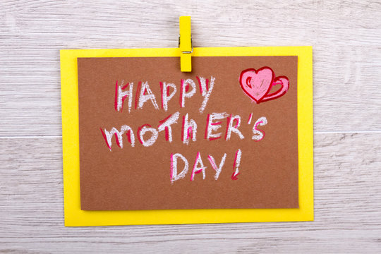 Congratulation card on Mother`s Day. Greeting card on wooden background. Mom will be happy. Happy celebration of holiday.