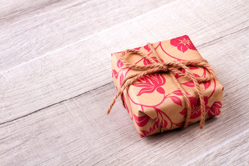 Box in wrap with rope. Gift lying on wooden surface. Tradition of sending gifts. Cute present for friend.