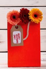 Flowers with tag in bag. Mother`s Day tag and gerberas. Impress mom with creativity. Simple handmade floral gift.