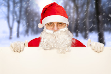 santa claus showing a blank billboard in a snowy forest
