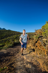 Male cross country athlete running in the hills on a warm and su