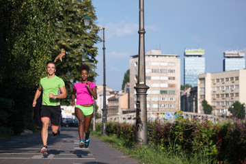 young smiling multiethnic couple jogging in the city