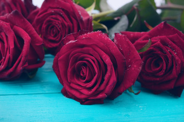 Bouquet of red roses on blue wooden table. Top view and copy space. Valentine day. Mock up. Selective focus