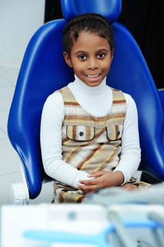baby girl with dark skin in blue dental chair