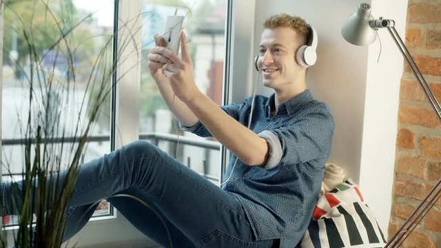 Man doing selfies while listening music by the window
