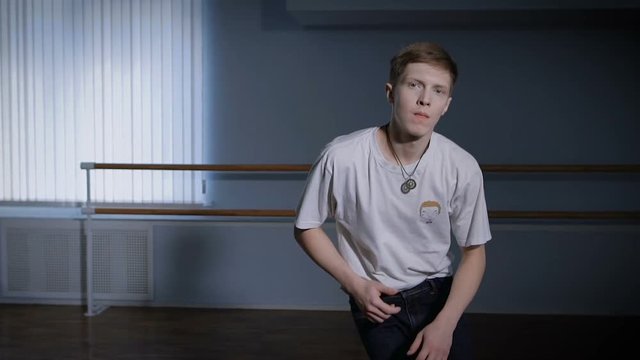 Close up of young hip-hop dancer in black trousers and white shirt performing toprock and other elements of breakdance. B-boy is jumping and doing cross step.