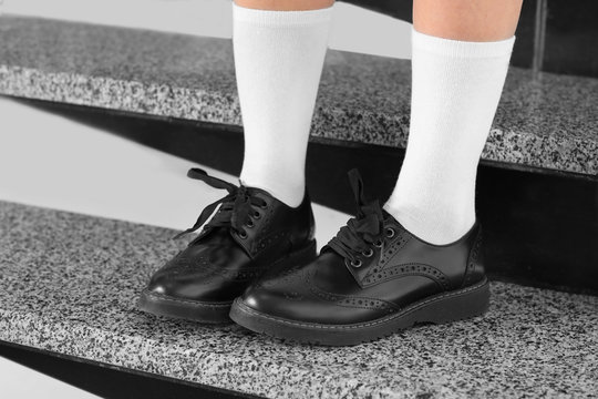 Feet of schoolgirl in uniform sitting on stairs, close up view