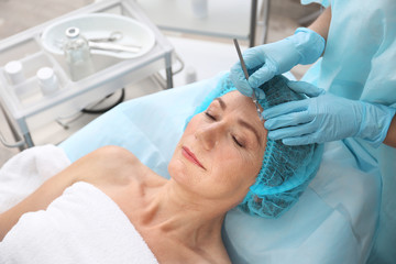 Obraz na płótnie Canvas Surgeon operating female patient with scalpel at beauty salon