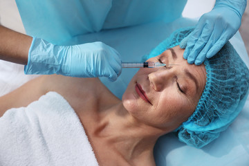 Senior woman having hyaluronic acid injection at beauty salon