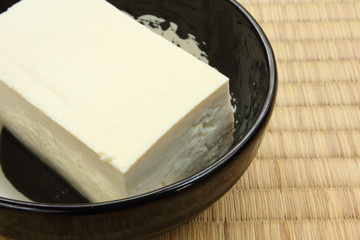 Tofu bean curd close-up on black round plate placed on tatami rice straw flooring mat