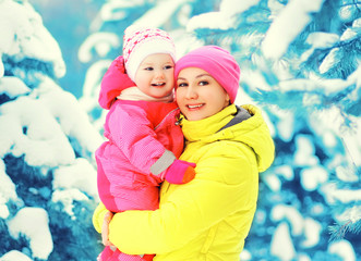 Winter portrait happy smiling mother holds baby on hands over sn