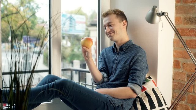 Rad haired man looking happy while throwing apple
