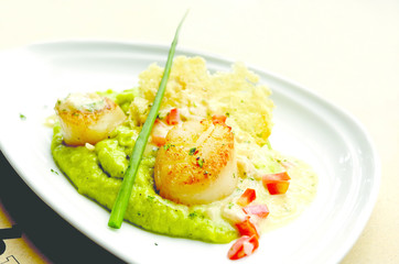 Close up of seared scallop with creamy mashed green pea. Selective focus.
