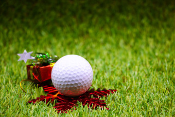 Golf ball with Christmas decoration on green grass
