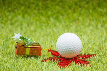 Naklejka premium Golf ball and Christmas ornament on green grass