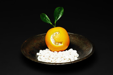 Orange with the letter c engraved, in a bowl with vitamin tablets, Letter c representing vitamin C