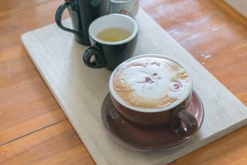 Close up white cup of Coffee with bear hand drawn on top, Coffee latte on the wooden.
