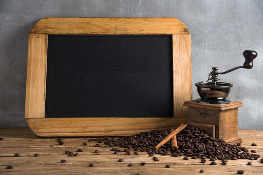 Antique vintage retro bronze coffee mill on wooden board with roasted coffee beans and menu board