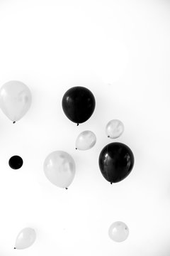 A floating balloon in the air inside a party room with backdrop in the background, in black and white.