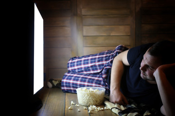 Naklejka premium young man watching television at home on the floor
