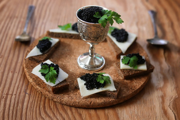 snack black caviar on a wooden background