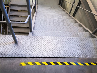 Attention. warning tape yellow and black on a concrete floor. Danger. Attention metal stairs....