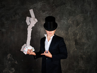 Illusionist man in tall hat with fountain of cards on a dark bac