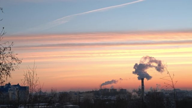 the smoke from the chimney of the plant against the dawn in the city.