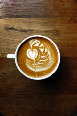 cup of latte art coffee on wooden background