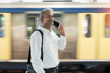 indian business male using smart phone with moving subway