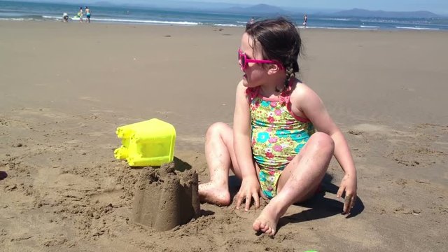 Little girl making a perfect sand castle on a golden sandy beach in North Wales.