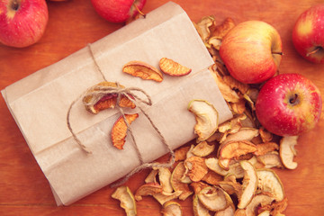Свежие и сушеные яблоки в пергаментной бумаге и на деревянном фоне