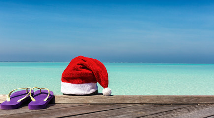 Weihnachts Mütze und Flip Flops auf Holzsteg vor tropischem Horizont