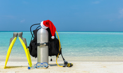 Taucherausrüstung mit Weihnachtsmütze am tropischen Strand