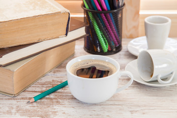 Office workplace with  coffee cup on wooden desk table in front of window with blinds, selective focus