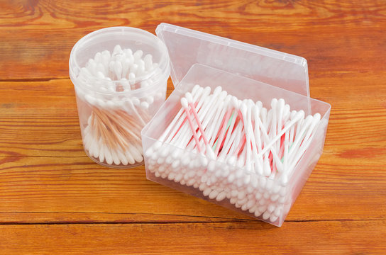 Two different plastic containers of cotton swabs on old planks