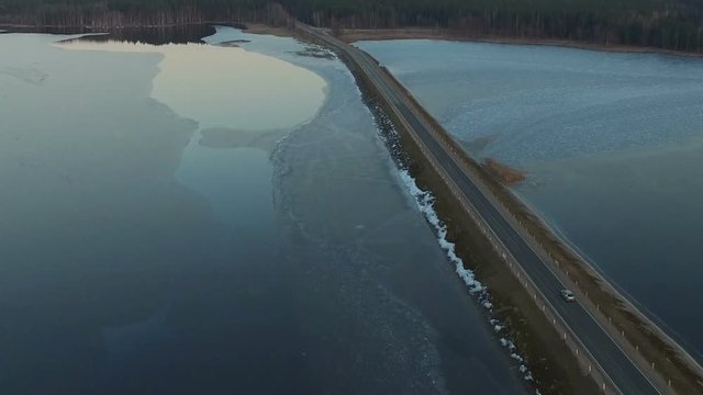 Flight over road in the frozen lake on sunset, winter aerial view.